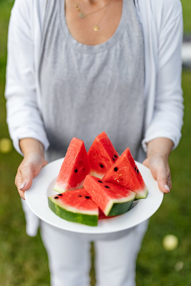 Mujer sosteniendo un plato lleno de sandía cortada a triángulos